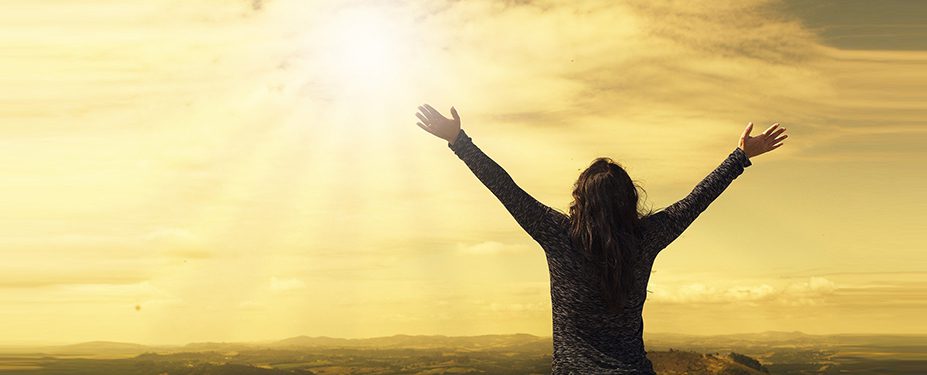 Person holding hands in air while looking at sun